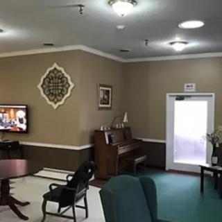 A cozy living room featuring a piano, TV, and comfortable seating arrangements.