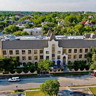 Aerial view of a multi-story building surrounded by lush greenery and residential areas.