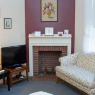 A cozy living room with a fireplace, sofa, and television.