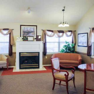 A cozy living room with a fireplace, elegant furniture, and large windows.