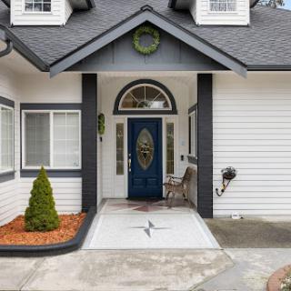 A welcoming entrance featuring a blue front door and well-maintained landscaping.