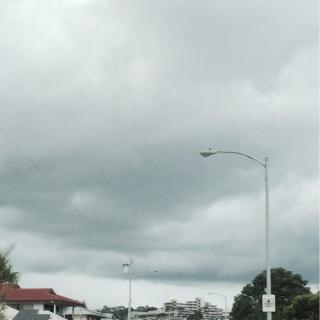 A cloudy, overcast sky above a street with a lamp post.