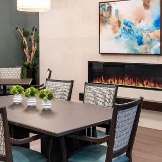A modern dining room with a sleek table and chairs, a contemporary fireplace, and abstract artwork on the wall.