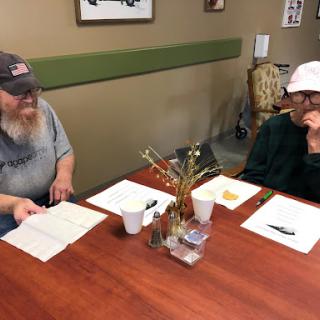 Two people engaged in a discussion over a table with some snacks and papers.