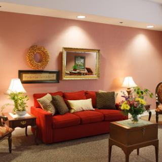 A cozy living room featuring a vibrant red couch, decorative pillows, and warm lighting.