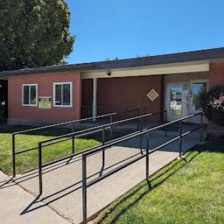 A building featuring a wheelchair-accessible ramp, surrounded by lush green grass under a clear blue sky.