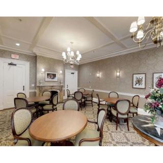 A well-decorated dining room with multiple tables and chairs, an elegant chandelier, and tasteful wall art.