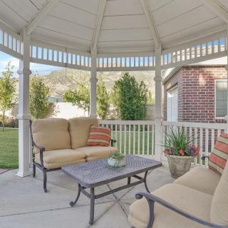 A cozy gazebo with comfortable seating and a table, surrounded by a landscaped garden.