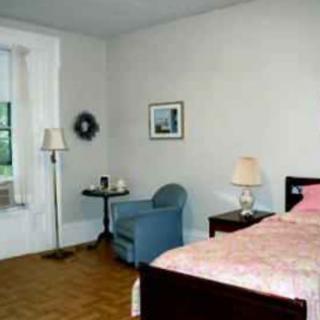 A simple bedroom with a bed, chair, and lamps.