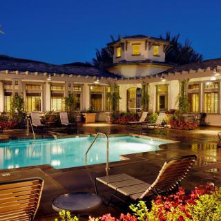 A luxurious house with a beautifully lit pool area at night.
