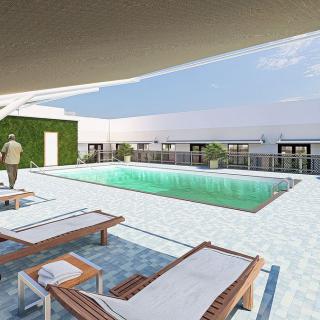 A rooftop swimming pool with lounge chairs and a view of the city skyline.