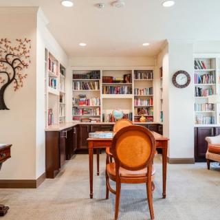 A cozy home library with bookshelves, a wooden table, and chairs.