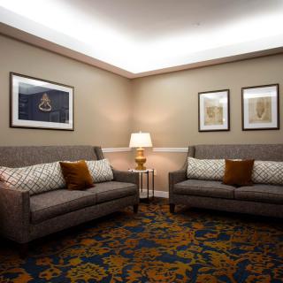 A cozy and elegantly decorated living room with two sofas, a central lamp, and framed artwork on the walls.
