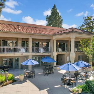 A scenic view of a modern building with outdoor seating and umbrellas on the patio.