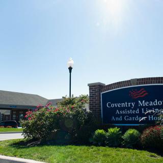 A welcoming sign at the entrance of a residential building with a clear blue sky.