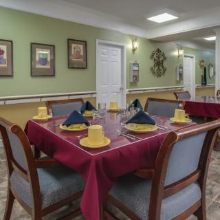 A neatly arranged dining table with yellow and blue napkins in a well-decorated dining room.