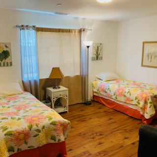 A cozy bedroom with two floral-patterned beds, wooden flooring, and decorative artwork.