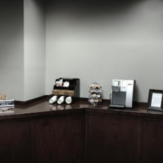 An office coffee station with cups and a coffee machine on a counter.