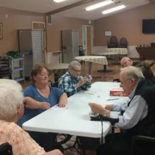 A group of seniors gathered around a table, engaged in conversation.