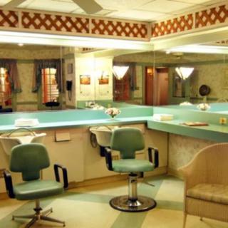 A vintage-style beauty salon with turquoise chairs and mirrored walls.