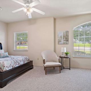 A cozy bedroom featuring a single bed, chair, and large windows with plenty of natural light.