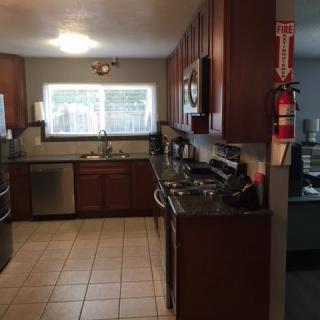 A modern kitchen with wooden cabinets, stainless steel appliances, and a tiled floor.