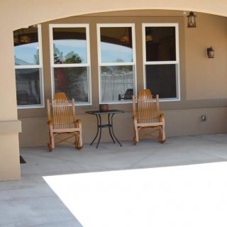 A serene patio with two wooden rocking chairs and a small table under an arched roof.