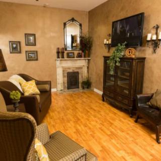A cozy living room with a fireplace, wooden flooring, and comfortable seating arrangements.