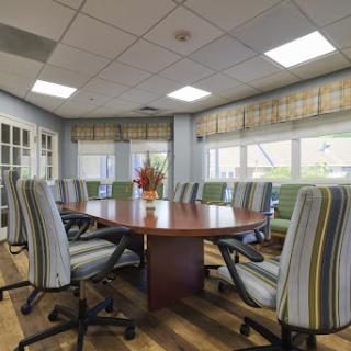A well-designed conference room featuring a large wooden table surrounded by comfortable striped chairs, ideal for meetings and collaborative discussions.
