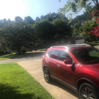 A red SUV parked in a driveway on a sunny day with trees in the background.