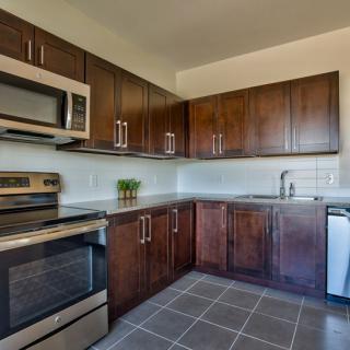 A modern kitchen with stainless steel appliances and dark wood cabinets.