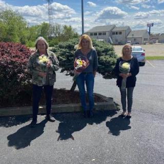 A joyful moment shared among friends, celebrating with beautiful flowers under a cloudy sky.