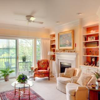 A cozy and well-lit living room with a sofa, armchair, and fireplace surrounded by built-in shelves.
