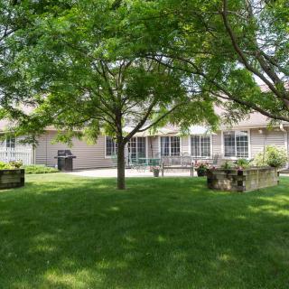 A serene backyard scene with lush green grass, trees, and a view of the house.