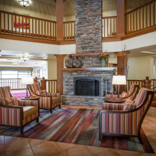 A cozy lobby area featuring a stone fireplace, surrounded by comfortable chairs and warm wood accents.