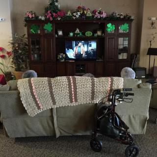 A cozy living room setup with a sofa, television, and a walker nearby.