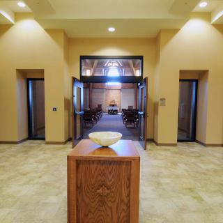 A symmetrical hallway leading to a well-lit room with wooden furnishings.