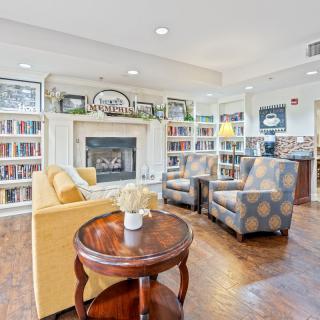 A cozy library space featuring a fireplace and comfortable seating surrounded by bookshelves.