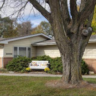 A cozy residential building with a large tree in the foreground.