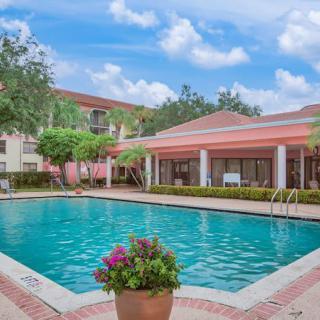 A serene outdoor swimming pool area surrounded by buildings and lush greenery.