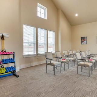 A spacious meeting room with rows of chairs arranged for a lecture, featuring large windows and ample natural light.