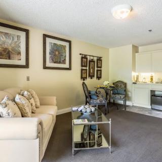 A cozy living space with a sofa, dining table, and kitchenette, decorated with framed artwork.
