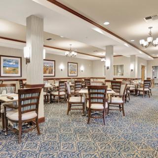 A spacious dining area with neatly arranged tables and chairs, featuring elegant decor and soft lighting.