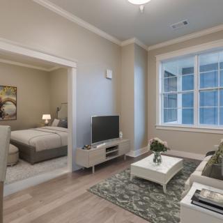 A modern living room with a view into the bedroom, featuring stylish furniture and neutral colors.