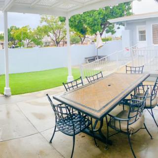 A cozy outdoor patio with a large table and chairs overlooking a small garden.