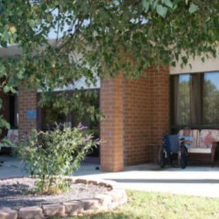 A quiet exterior of a brick building with landscaping and benches.