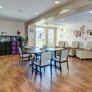 A cozy living area with chairs and a table, adorned with decorations and large windows.