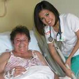 A nurse attending to a patient in a hospital bed.