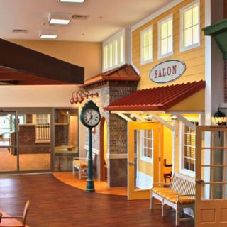 An indoor space designed to resemble a village street with colorful shopfronts and a decorative clock.