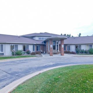 A residential building with a circular driveway and landscaped front area.